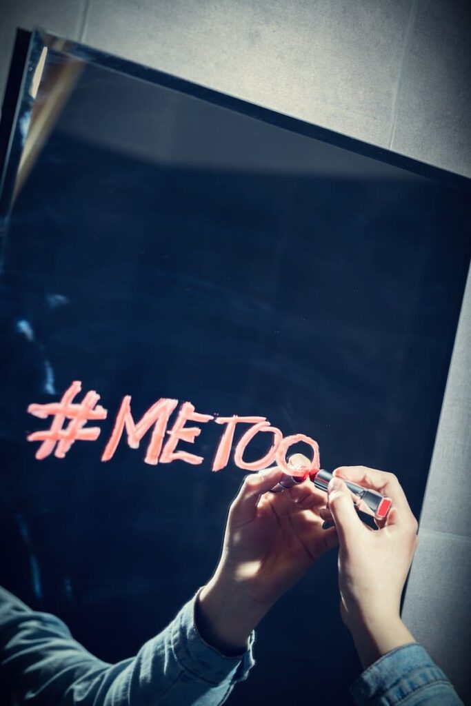 אדם כותב "MeToo#" על מראה עם שפתון אדום.